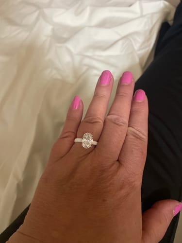 A customer's hand wearing the Rinfit Thin Silicone Ring, which has a white band and a large oval-cut stone.