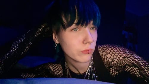 Reviewer with blue-streaked hair wearing the silver Octopus Earring in a dimly lit setting.