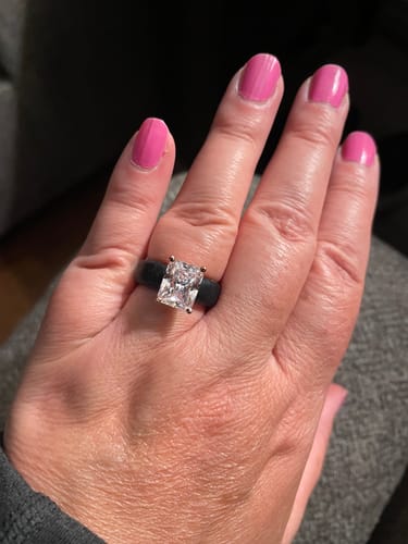 Customer's hand wearing the black silicone ring with a large, brilliant emerald-cut stone.