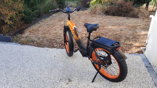 Reviewer's black and orange Lankeleisi MG600 Plus fat bike parked on a paved driveway.
