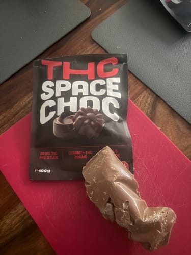 Rezensent zeigt die Verpackung und den geschmolzenen Block THC SpaceChoc Schokolade.