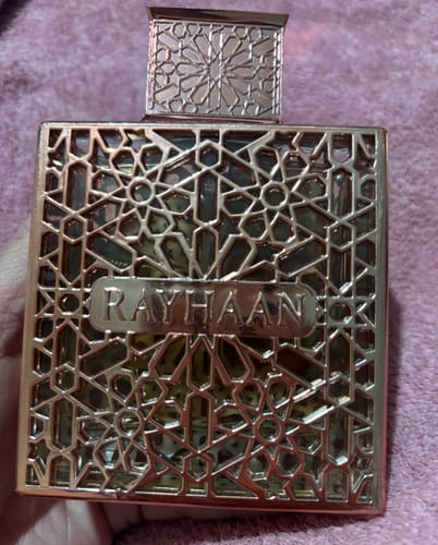 Cliente sosteniendo el frasco del perfume Rayhaan Divine, que tiene una elaborada funda metálica.