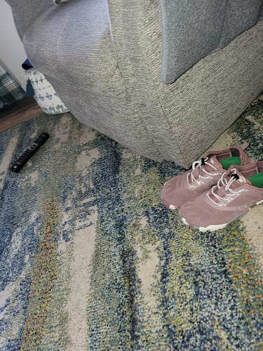 Reviewer's pink Smart II - Barefoot Shoes on a colorful rug in a living room.
