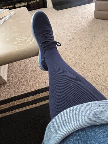 Reviewer's leg propped up, wearing dark blue, ribbed Eucalyptus Lyocell Compression Socks with a sneaker.
