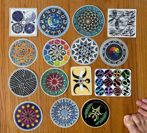 Reviewer's assortment of colorful, intricate stickers with white borders laid out on a wooden surface.