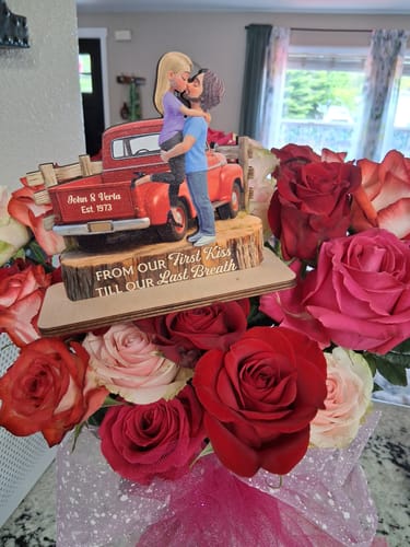 Customer's personalized wooden plaque with a couple kissing by a red truck, presented in a bouquet of roses.