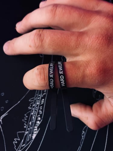 Customer using two black Hard Jewelry FREE RING SIZERs on their finger to find the right size.
