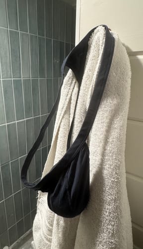 A customer's blue Modal Thong hanging on a white towel in a bathroom setting.