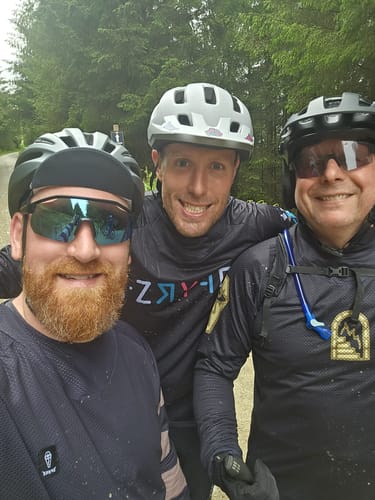 Three customers posing for a photo in their black, long-sleeved cycling jerseys.