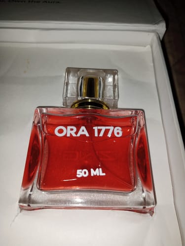 Customer's ORA 1776 perfume bottle, showing the red liquid and 50 ML size, resting inside its white box.