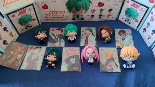 Customer's Alien Stage figurines and their collectible cards displayed on a blue surface with the blind boxes in the background.
