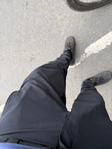 Reviewer's first-person view of the black Tyrant Trail Trousers, showing the fit while standing outdoors.
