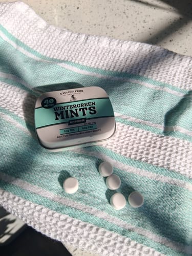 Customer's tin of Wintergreen Mints with several white mints displayed on a striped towel.