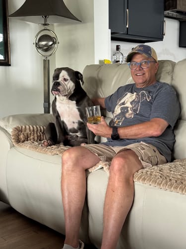 Customer wearing the American Bulldog t-shirt while sitting on a sofa next to his dog, which matches the shirt's graphic.