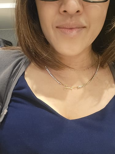Close-up of a reviewer wearing their personalized Signature Name Tennis Necklace against their skin.