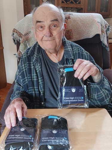 A reviewer holds up one package of Eucalyptus Lyocell Compression Socks with two others on a table.