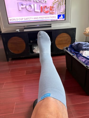 Customer wearing a light blue Eucalyptus Lyocell Compression Sock on their leg while resting at home.