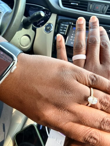 Customer's hands together, one wearing the sparkling Opaline ring with an oval stone and pavé band.