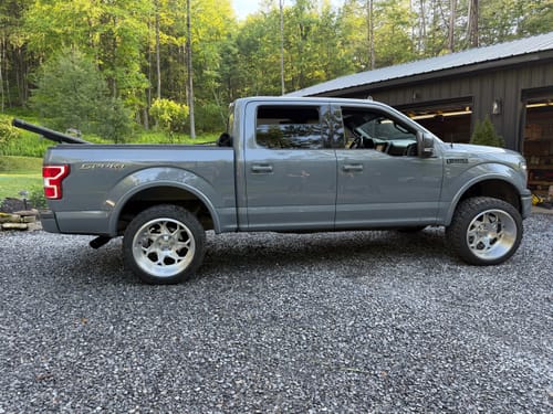 Customer's grey Ford F150 shown from the side with the 2.5" lift kit and large custom wheels installed.