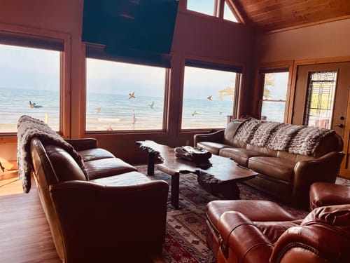 Customer's two plush Hugs Antelope Blankets, one on each leather sofa in a sunlit room by the water.