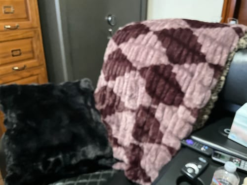 Customer's plush Hugs Shelby Mulberry Diamond Blanket with its cozy diamond pattern draped over a chair.