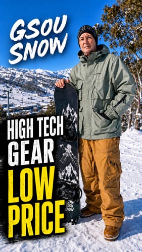 Reviewer standing in the snow wearing the baggy caramel snow pants and holding a snowboard.