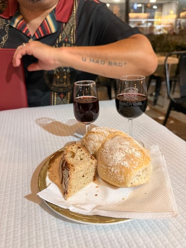 Customer wearing the black and red El Jefe Azteca Guayabera shirt while sitting at a dinner table with wine and bread.