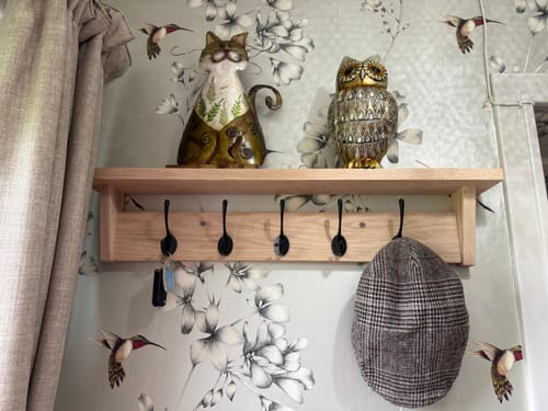 Customer's solid oak coat rack with shelf mounted in a hallway, holding decorations on the shelf and a cap on a hook.