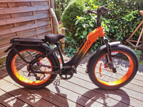 Customer's Lankeleisi MG600 Plus e-bike with a black frame and bright orange details parked on a wooden deck.