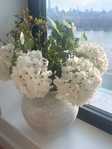 Customer's Arina Vase with a stone texture, filled with elegant white flowers and greenery on a windowsill.