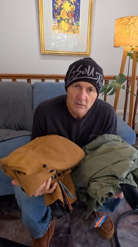 Reviewer sitting on a couch showing outdoor gear from their recent purchase.