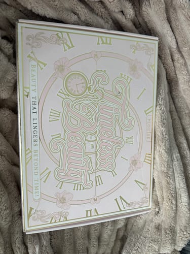 Customer's Budget Box with a pink and white 'Timeless Beauty' clock design, shown closed on a blanket.