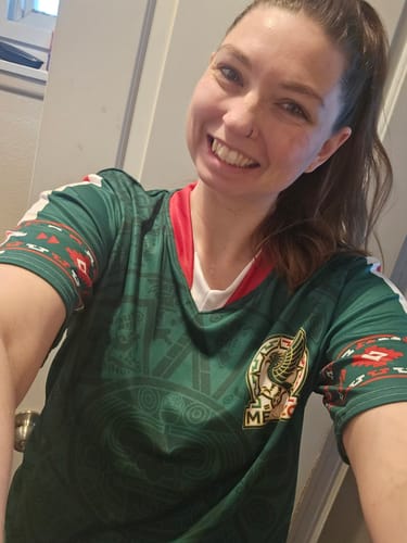 A smiling reviewer wears the green Azteca Xiuhpohualli Mexico Fútbol Jersey, showing the front design and crest.
