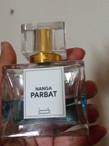 Customer holding the clear glass Nanga Parbat perfume bottle, showing the light blue liquid inside.