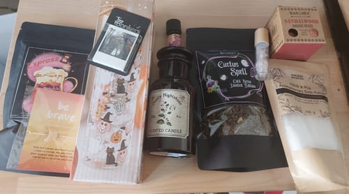 Rezensent zeigt den ausgepackten Inhalt der Witchy Box, darunter eine Kerze, einen Becher und verschiedene magische Artikel.