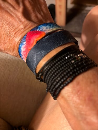 Customer's wrist with the stacked Iron Sharpens Iron bracelet, showing its dark outer band and colorful inner design.