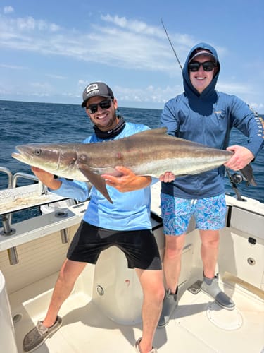 Reviewer, a charter fishing guide, smiling and holding a large fish on a boat with another person.
