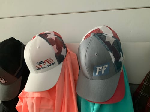 Customer's White Stars and Stripes Hat hanging on a wall next to another similar patriotic-themed hat.