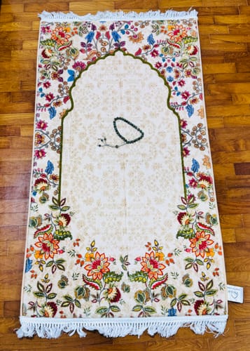 Customer's Barakah Padded Prayer Mat laid out on a floor, showing its colorful floral design and a complimentary tasbeeh.