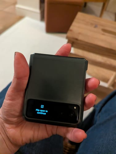Customer holding the compact Motorola Razr 40 folded shut in their palm, with the cover screen on.