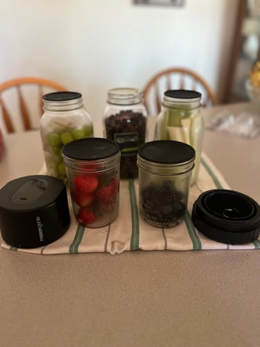 Customer's Mason Genie Vacuum Sealer Kit next to several glass jars filled with fresh produce like strawberries and grapes.