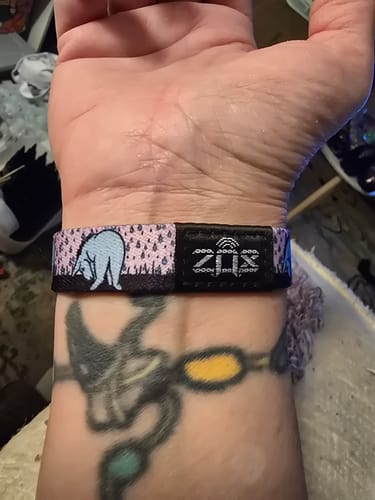 Close-up of a reviewer wearing the purple patterned Storms Don't Stay Bracelet on their wrist, showing the Eeyore design.