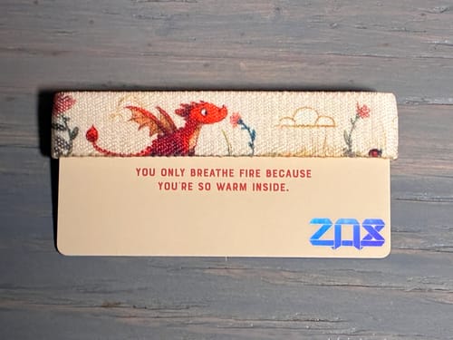 Reviewer's woven Softy Inside Bracelet with a cute red dragon design, shown on its collector's card.