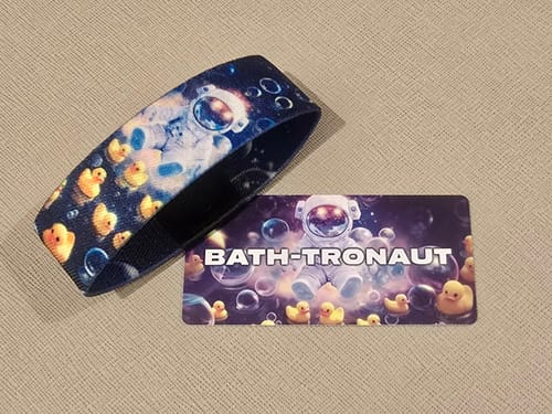 Customer's Bath-tronaut Bracelet and matching collector's card laid out, showing the playful astronaut and rubber duck design.
