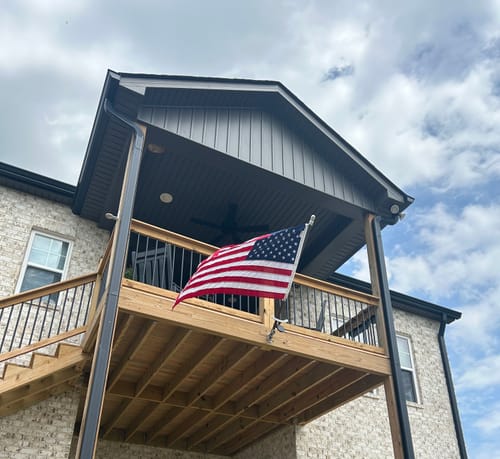 Reviewer's Prestige House Flag Pole with an American flag, mounted to an elevated wooden deck on a cloudy day.