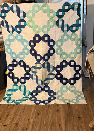 Reviewer's pieced Ribbon Rings quilt top in shades of blue and green, shown before adding the border.