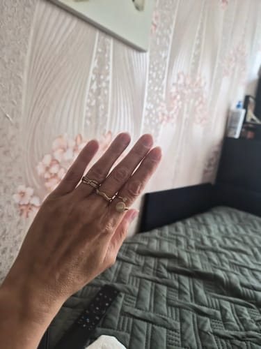Kliento ranka, ant kurios piršto mūvimas tyrumo žiedas „Calmy“ tarp kitų žiedų.