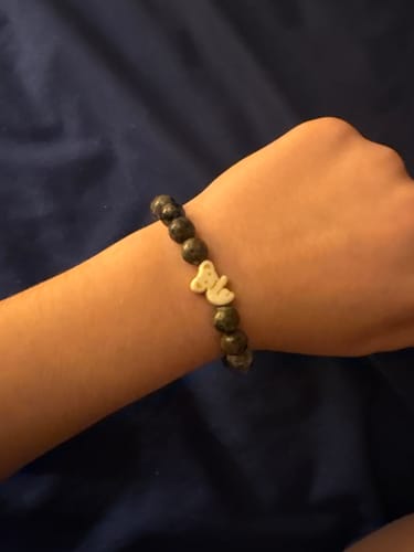 Reviewer wearing a Fahlo bracelet with dark mottled beads and a light-colored animal charm on their wrist.