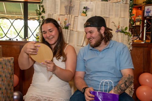 Customer at an event looking at the back of the personalized wooden plaque as a man smiles beside her.