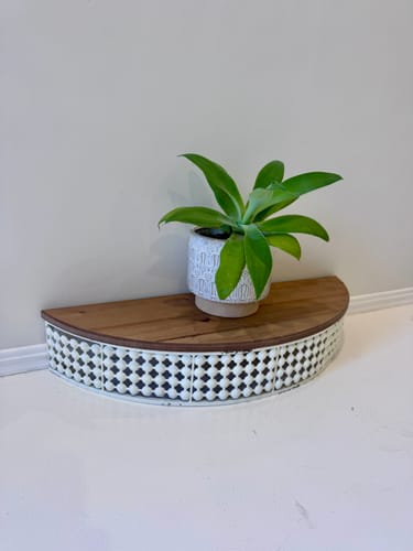 Customer's Rolande Half Moon Wall Shelf on a white floor, holding a small potted plant on its wood top.